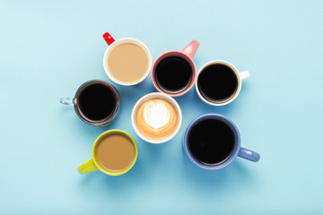 Many multicolored cups of coffee and coffee drinks on a blue background. Concept breakfast with...