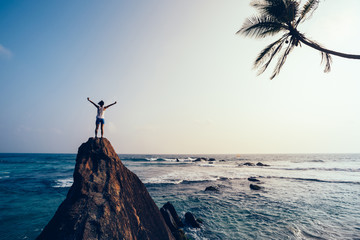 Freedom young woman outstretched arms on seaside rock cliff edge