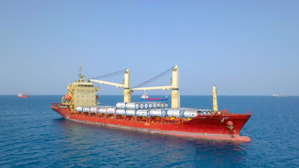 Large general cargo ship loaded with gas containers - Top down aerial image.