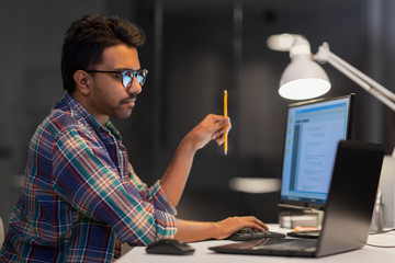 deadline, technology and people concept - creative man in glasses working with laptop computer at...