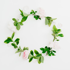 Floral round frame of pastel pink roses and green leaves on white background. Flat lay, top view. Spring time composition