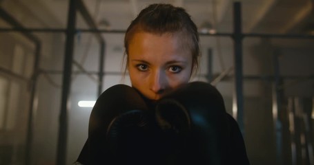 Portrait of female boxer looking into camera at a boxing studio. 4K UHD
