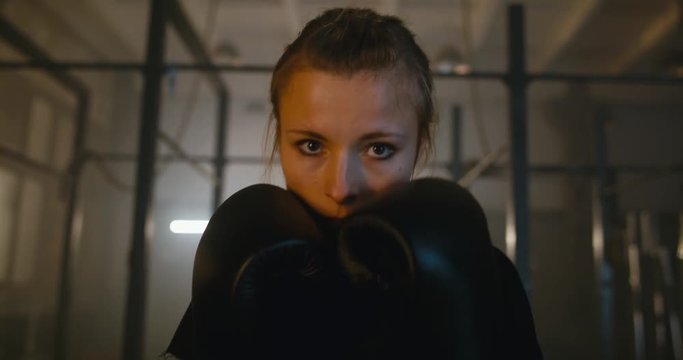 Portrait of female boxer looking into camera at a boxing studio. 4K UHD