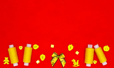 Yellow bright accessories for sewing on a red background.