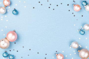 Christmas frame made of Christmas balls and silver confetti on blue background. Minimal New Year...