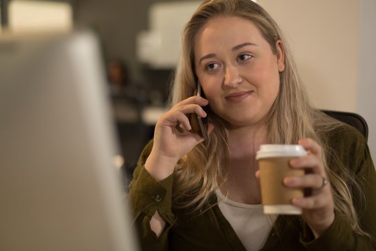 Executive talking on mobile phone while having coffee