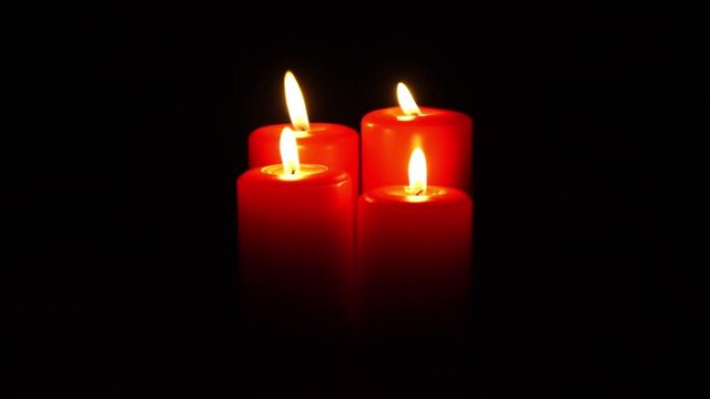 four red christmas candles burning with flickering flame