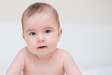Little cute baby is crawling on a white bed
