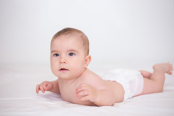 Little cute baby is crawling on a white bed