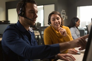 Customer service executives discussing over desktop pc