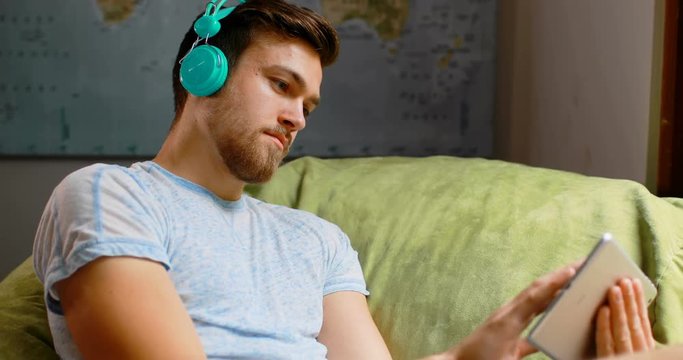 Man listening music on digital tablet at home 4k