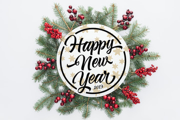 top view of pine tree wreath with Christmas decorations with "happy new year 2019" lettering in middle isolated on white