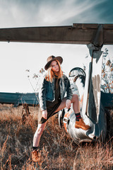 Stylish girl stands next to an abandoned aircraft field.  Model in dress, jacket, shoes