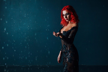 Gothic girl with red hair looking at the camera.  Model in a black dress