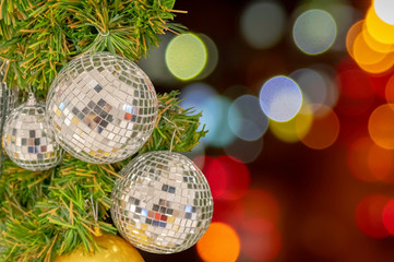 Glass ball ornaments on a Christmas tree and blurred lights.