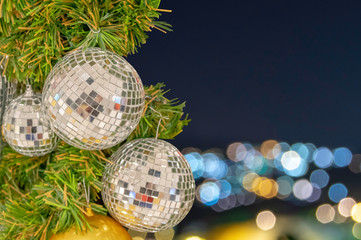 Glass ball ornaments on a Christmas tree and blurred lights.