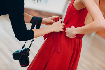 Photographer helps model woman before photoset.