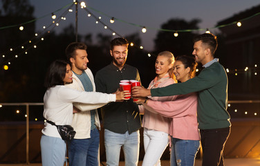 leisure, celebration and people concept - happy friends with drinks toasting at rooftop party at...