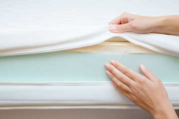 Woman's hands touching different layers of new mattress. Checking hardness and softness. Choice of the best type and quality. Front view. Close up. - obrazy, fototapety, plakaty