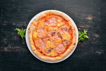 Pizza with ham and Parmesan cheese. On a wooden background. Top view. Free space for your text.