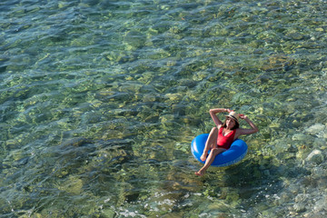 Beautiful young woman with inflatable ring relaxing in the sea.