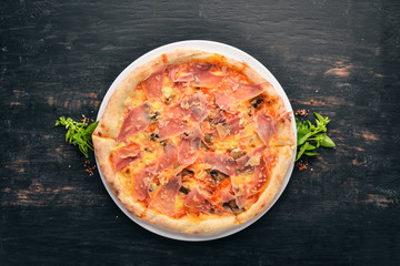 Tasty pizza with prosciutto, parmesan cheese and mushrooms. On a wooden background. Top view. Free copy space.