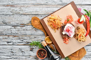 Beefsteak. Veal with poached egg and tomato juice. On a wooden background. Top view. Free space for your text.