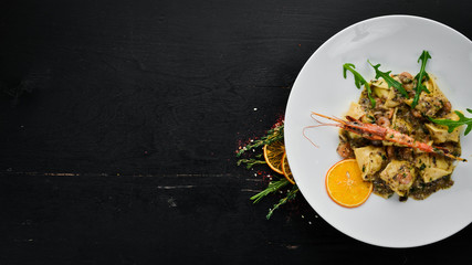 Ravioli with shrimp and seafood. Italian cuisine. Dumplings. In a plate on a wooden background. Top view. Free copy space.