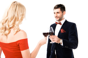 Back view of woman in beautiful red dress and man with glasses of red wine isolated on white