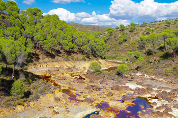 River polluted by gold mine in dry valley with trees, Río Tinto in Huelva, Andalucía, Spain