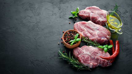 Raw steak. Meat with spices and herbs. On a black stone background. Top view. Free copy space.