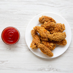 Chicken wings on a round white plate with red pepper sauce over white wooden background, top view. From above, flat lay, overhead.