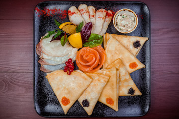 Pancakes with red and black caviar, with red fish and various sauces