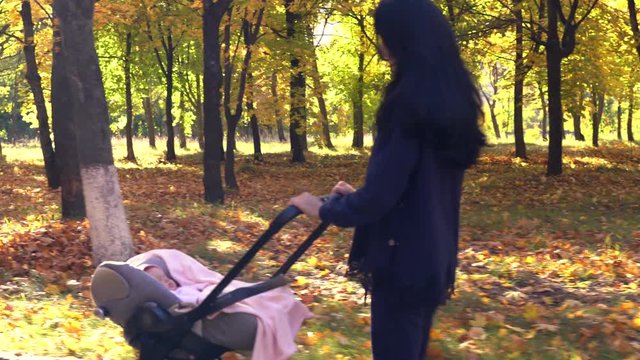 Woman walking with baby stroller in park