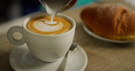 Macro of a barman while making a cappuccino next to the coffee machine in a typical italian bar. Concept: Concept: art, passion, love