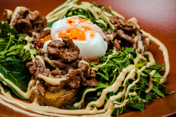 Hot appetizer salad with potatoes, meat, green peas, poached egg