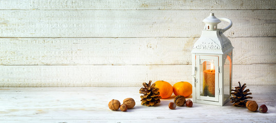 candle light lantern with pine cones, nuts and tangerines as christmas decoration on a wide, bright...