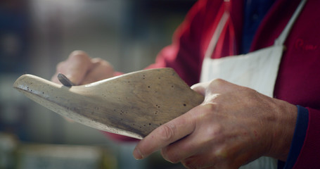 Close up of a shoemaker while he is sanding a silhouette of a shoe by using the Italian tradition, in a shoe factory. Concept: handmade, fashion, industrial, factory.
