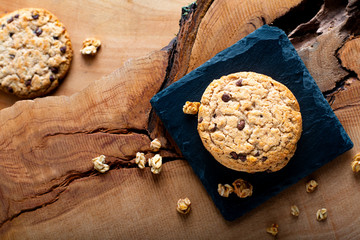 Food concept homemade organic chocolate chips cookie on slate stone plate on rustic wooden background with copy space