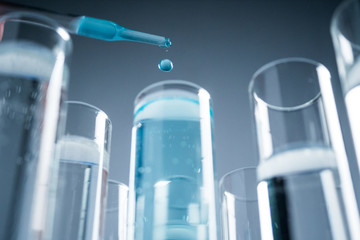 In a futuristic laboratory, a scientist with a pipette analyzes a colored liquid to extract the DNA and molecules in the test tubes.Concept:research,biochemistry,immersive technology,augmented reality