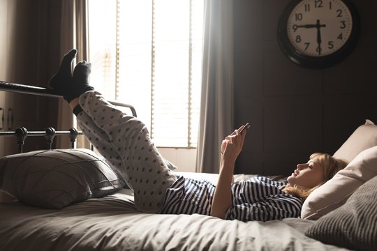 Teenage Girl Using Cell Phone On Bed In Bedroom