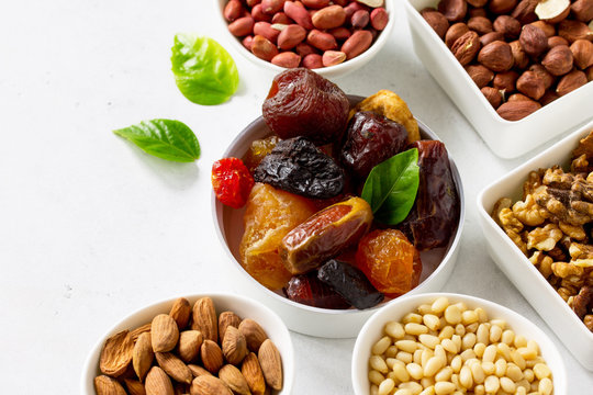 Various Nuts in a ceramic bowl and Dried Fruits on a light stone table. The Concept of a Healthy Dessert.