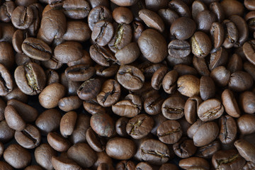 Coffee grains texture. The structure of the many scattered, fragrant coffee beans. Common, brown grains of ripe coffee for an invigorating morning drink.