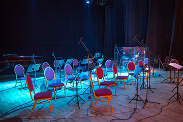 Music stands, microphones, musical instruments and chairs at a concert stage