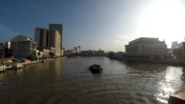 Carrier ship sailing toward bridge on huge, murky Pasig River early morning