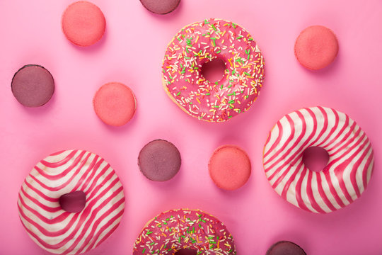 Donuts and macaroons on a pink background.