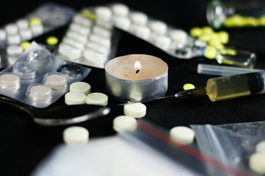 Drugs on a black background. Syringe, needle, pills, white powder, candle, spoon. Close up.