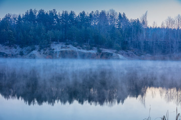 Early misty morning. Dawn over the lake with the rocky shore