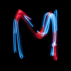 Obraz na płótnie Canvas Letter M of the alphabet made from neon sign. The blue light image, long exposure with colored fairy lights, against a black background