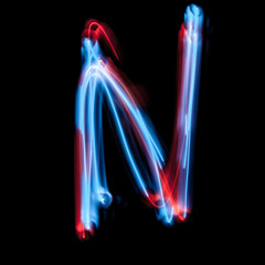 Letter N of the alphabet made from neon sign. The blue light image, long exposure with colored...